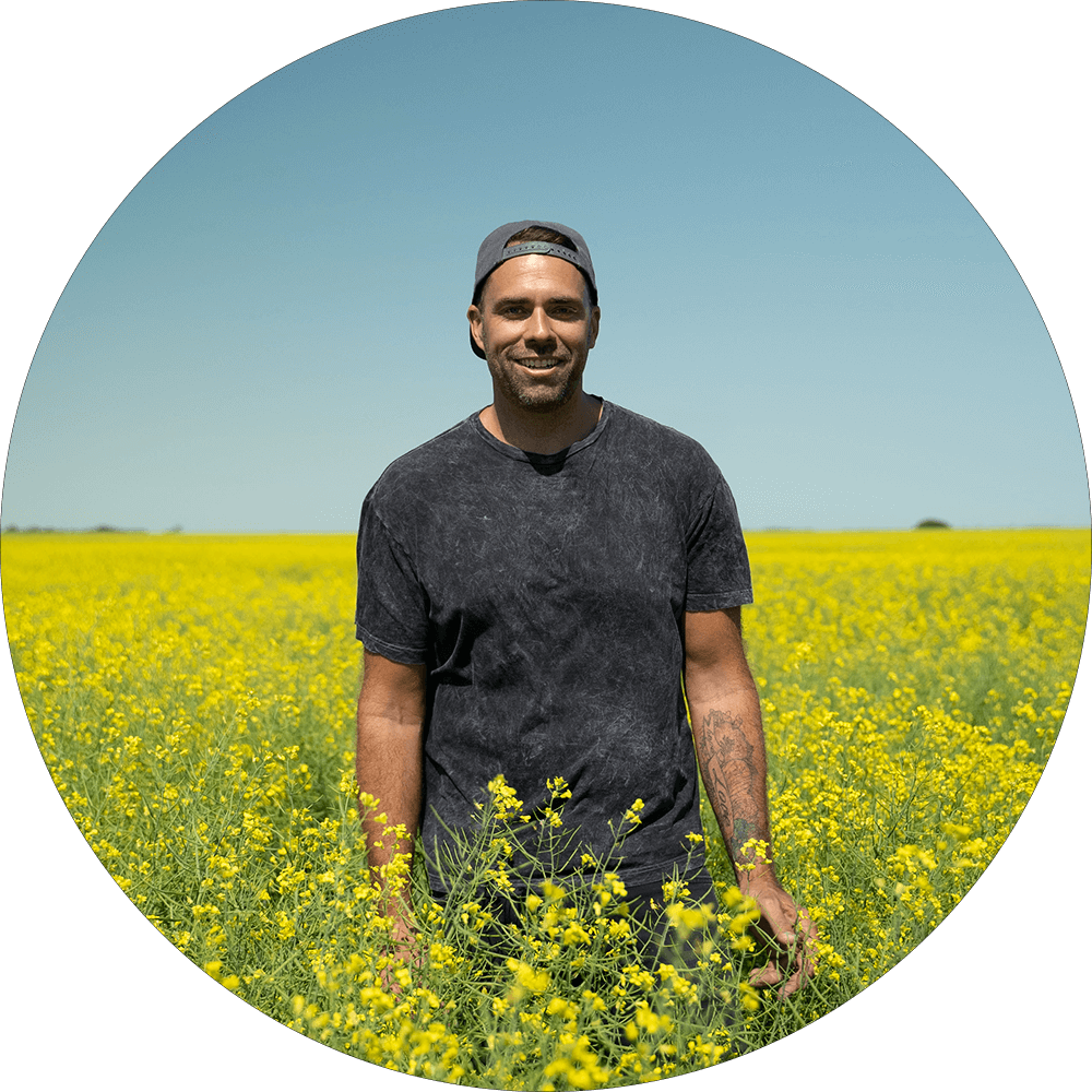 Will Bergmann standing in a field of canola Will Bergmann standing in a field of canola