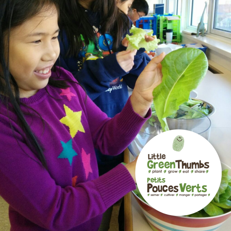 Two students holding plants in classroom 